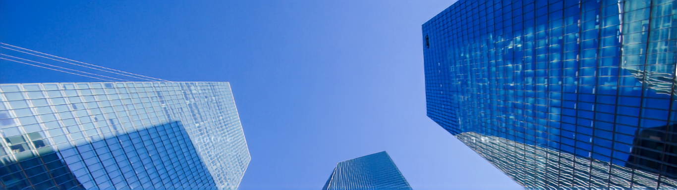 Glass office towers seen from below against a blue sky